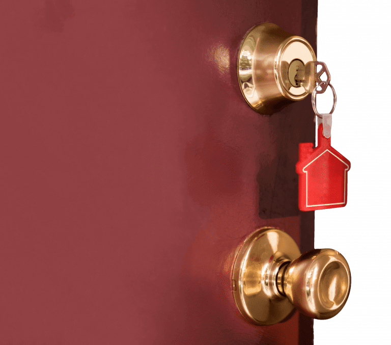Door with key inside the lock with a house-shaped keychain.